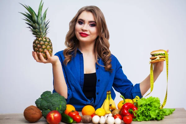 Kvinna gör ett val mellan hälsosam och skadlig mat. — Stockfoto