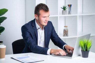 Şirket ofisinde çalışan yakışıklı genç bir işçi. Belgeleri ve bilgisayarı var.