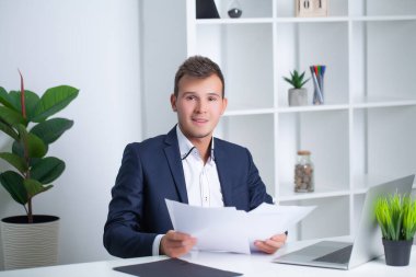 Şirket ofisinde çalışan yakışıklı genç bir işçi. Belgeleri ve bilgisayarı var.