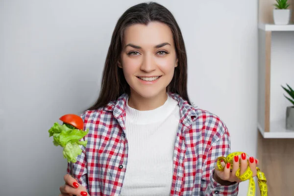 Vacker kvinna som gör ett val mellan nyttig och skadlig mat — Stockfoto