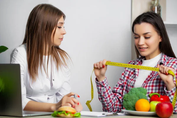 Mulher bonita que faz uma escolha entre alimentos úteis e prejudiciais — Fotografia de Stock