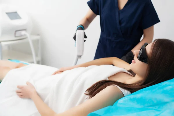 Hermosa mujer en el estudio de belleza consiguiendo procedimiento de depilación láser —  Fotos de Stock