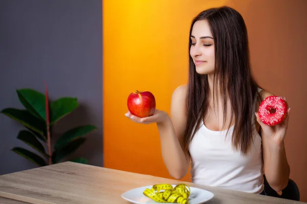 Beautiful woman who makes a choice between useful and harmful food — Stock Photo, Image