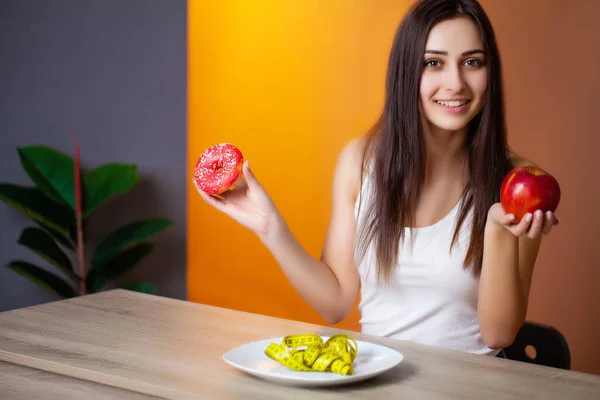 Beautiful woman who makes a choice between useful and harmful food — Stock Photo, Image