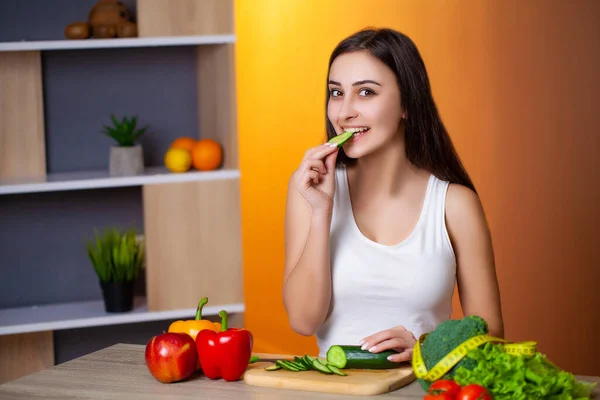 Cute woman slices cucumber for diet salad. — Stock Photo, Image