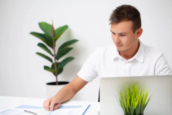 Beau jeune travailleur travaillant dans un bureau d'entreprise avec des documents et un ordinateur portable — Photo