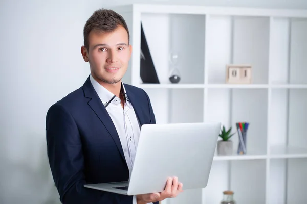 Hübscher junger Arbeiter, der in einem Firmenbüro mit Dokumenten und Laptop arbeitet — Stockfoto