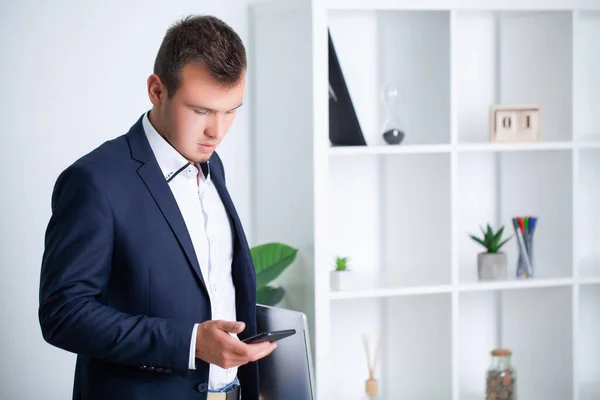 Fešák mladý pracovník používá telefon v kanceláři společnosti — Stock fotografie