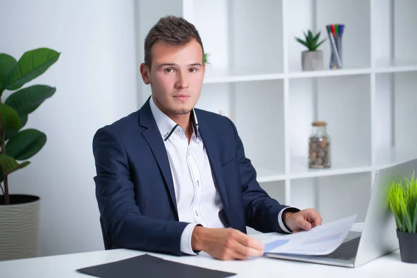 Beau jeune travailleur travaillant dans un bureau d'entreprise avec des documents et un ordinateur portable — Photo