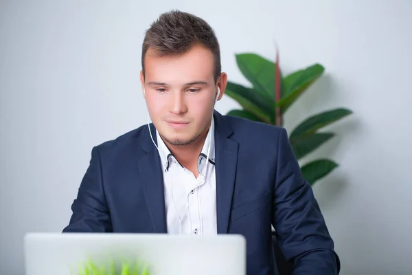 Knappe jonge werknemer die werkt in een kantoor met documenten en een laptop — Stockfoto