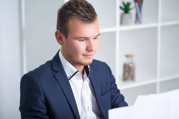 Bel giovane lavoratore che lavora in un ufficio aziendale con documenti e un computer portatile — Foto Stock