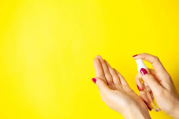 Žena používá antiseptika na žlutém pozadí — Stock fotografie