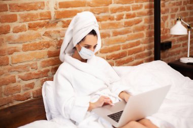 Kadın salgın sırasında evde kalır ve dizüstü bilgisayarla çalışır.