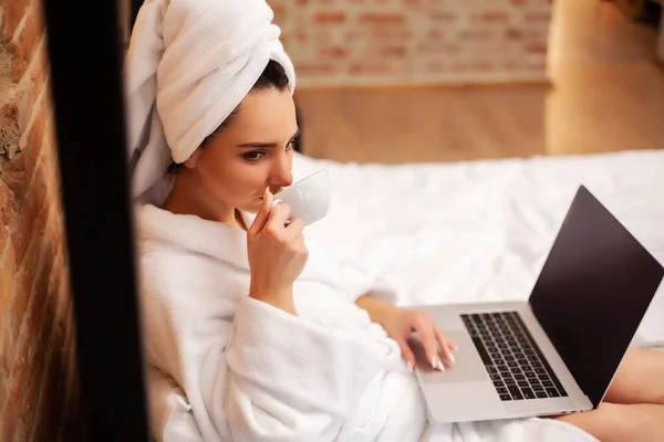 Cute woman stay at home and working at a laptop drinking coffee