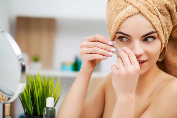 Leuke vrouw in de badkamer gebruik pleisters voor gezichtsverzorging — Stockfoto