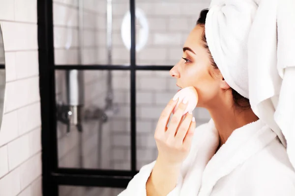Красива жінка робить косметичні процедури для догляду за шкірою обличчя у ванній — стокове фото