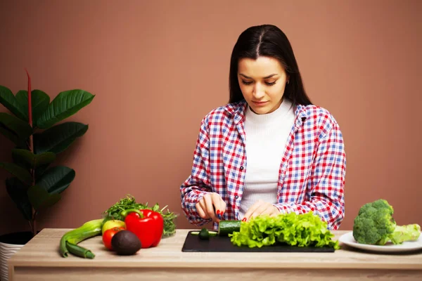 Vacker kvinna förbereder en sallad med färska grönsaker hemma i köket — Stockfoto