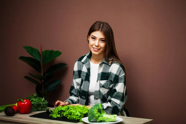 Vacker kvinna förbereder en sallad med färska grönsaker hemma i köket — Stockfoto