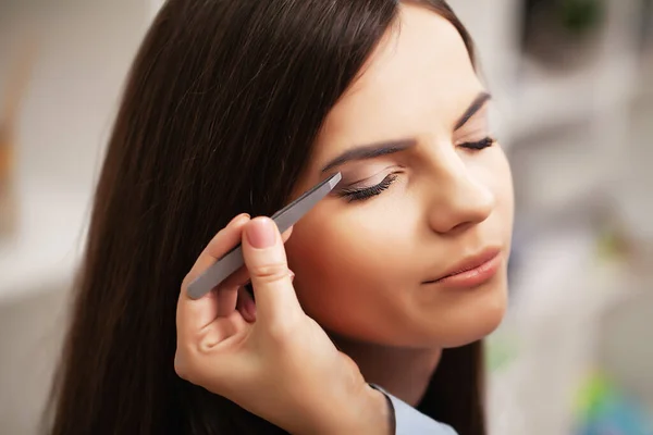 Chica bonita utiliza los servicios de un artista de maquillaje profesional en un estudio de belleza — Foto de Stock