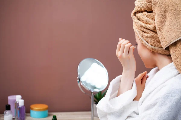 Chica bonita haciendo procedimientos cosméticos en casa delante del espejo . — Foto de Stock