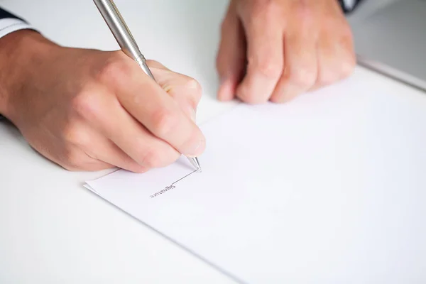 Businessman sitting at office desk signing contract. — Stock Photo, Image