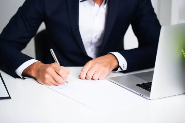 Businessman sitting at office desk signing contract. — Stock Photo, Image