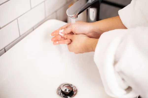 Femme se lave les mains dans une salle de bain lumineuse . — Photo