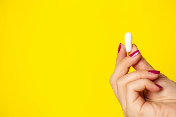 Žena drží bílou pilulku v ruce na hubnutí — Stock fotografie