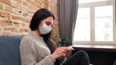 Genç kadın evde kalıp sıcaklığı elektronik termometreyle ölçüyor.
