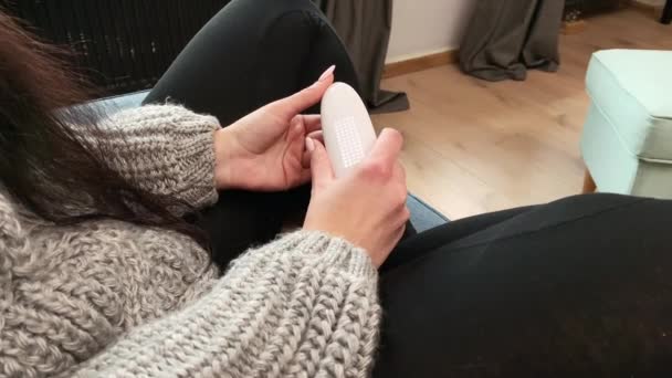 Young woman stays home and measures the temperature with an electronic thermometer — Stock Video