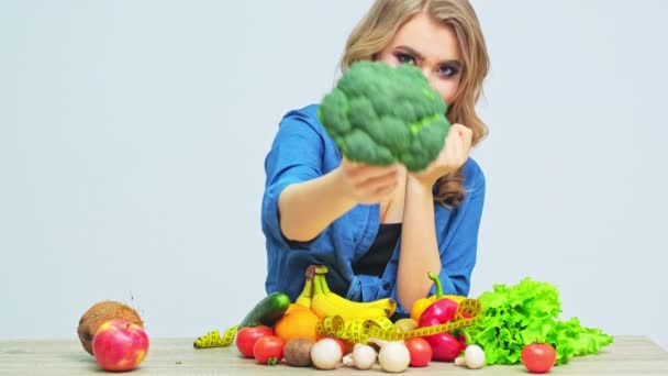 Молодая женщина на строгой диете на фоне свежих овощей и фруктов — стоковое видео