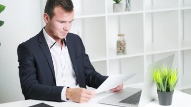 Ofisteki belgelerle çalışan genç adam.