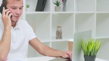 Bilgisayarın parlak ofisinde çalışan genç adam.