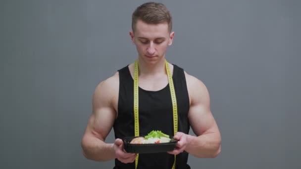 Junger Sportler mit einer proteinreichen Mahlzeit in der Hand — Stockvideo