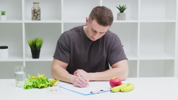 Jovem desportivo treinador masculino elabora um plano de dieta — Vídeo de Stock