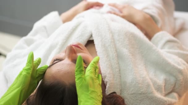 Joven hermosa mujer asiste al spa y recibe masaje facial — Vídeo de stock