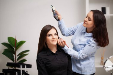Makyaj sanatçısı müşterisine profesyonel makyaj yapıyor.
