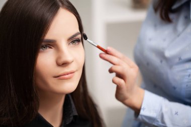 Makyaj sanatçısı müşterisine profesyonel makyaj yapıyor.