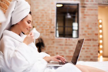 Duştan sonra dizüstü bilgisayarla sohbet eden güzel bir kadın.