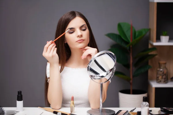 Frau schminkt sich zu Hause vor Spiegel im Schlafzimmer — Stockfoto