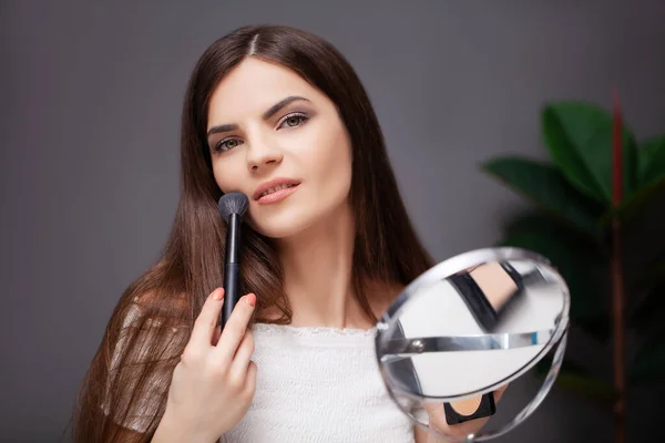 Mujer haciendo maquillaje en casa delante del espejo en el dormitorio —  Fotos de Stock