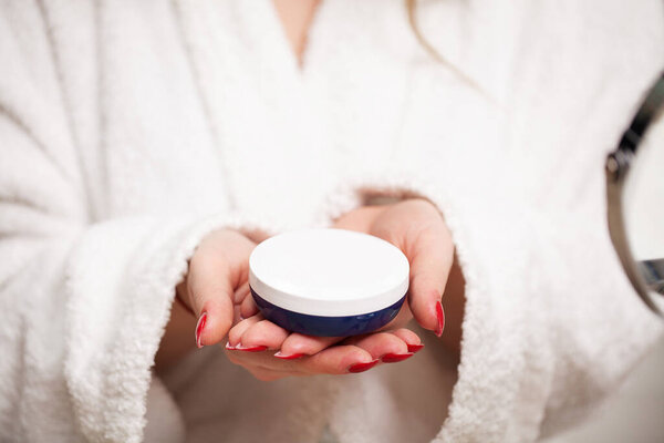 Крупный план девушка кладет крем для лица на руку
.