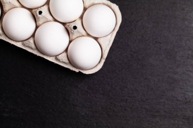 Siyah bir masada pakette tavuk yumurtası.