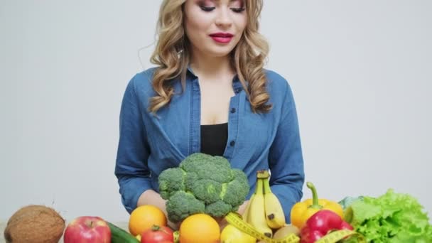 Egészséges ételek otthon, nő a konyhában friss zöldségekkel és gyümölcsökkel a fehér falon háttér — Stock videók