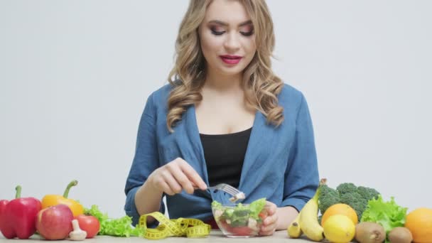 Gezond eten thuis, vrouw in de keuken met verse groenten en fruit op een witte muurachtergrond — Stockvideo