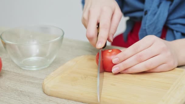 Όμορφη γυναίκα στην κουζίνα κόβει μια ντομάτα για μια φρέσκια σαλάτα — Αρχείο Βίντεο