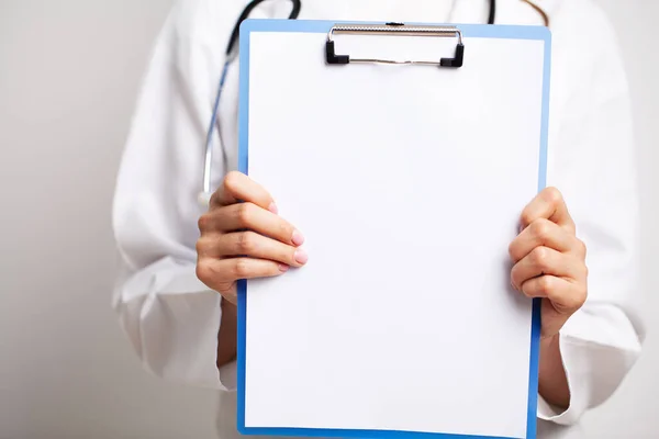 Médico segurando uma folha de papel em branco com espaço para texto — Fotografia de Stock