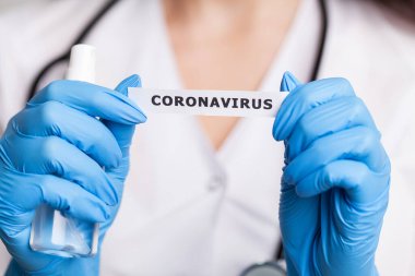Beyaz önlüklü kadın doktor Coronavirus yazısını tutuyor.