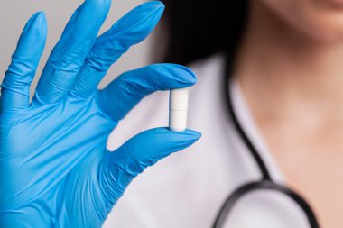 Beyaz önlüklü kadın doktor kilo vermek için beyaz hap tutuyor.