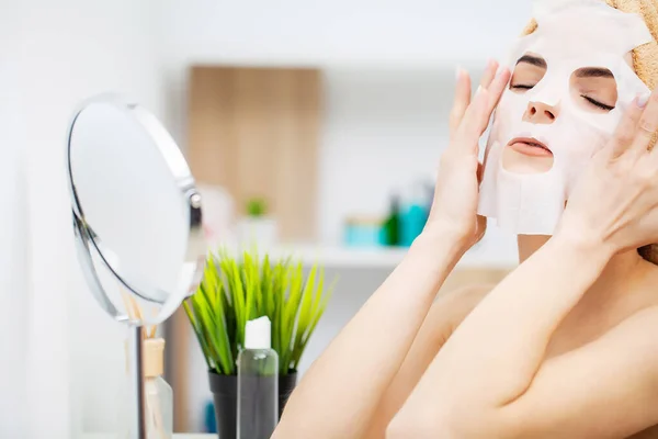 Wanita mengenakan masker wajah untuk perawatan kulit di kamar mandi — Stok Foto